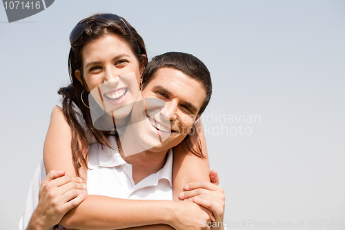 Image of Happy young guy piggybacking his girlfriend