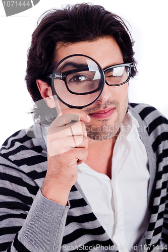 Image of young man looking stright with a magnifying glass