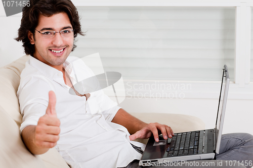 Image of young man using laptop showing thumbs up
