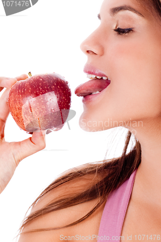 Image of closeup of young girl tasting the apple by her tounge