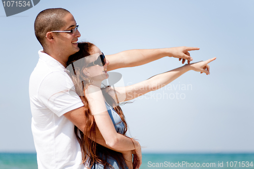 Image of Couple holding each other and pointing at the sea