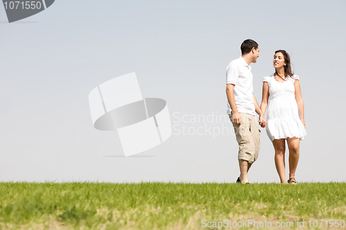 Image of Lovely young couple holding hands and walking