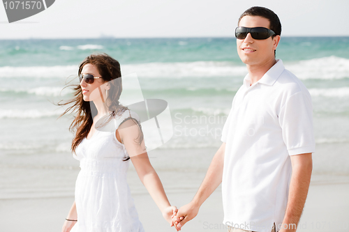 Image of Young couple holding hands and walking by the beach