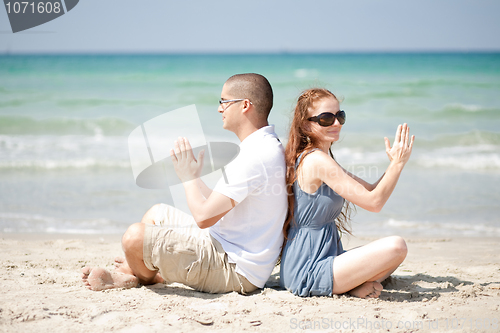 Image of Couple doing exercises on the beach sand