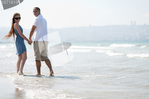 Image of Lovely Couple walking at the beach and look back