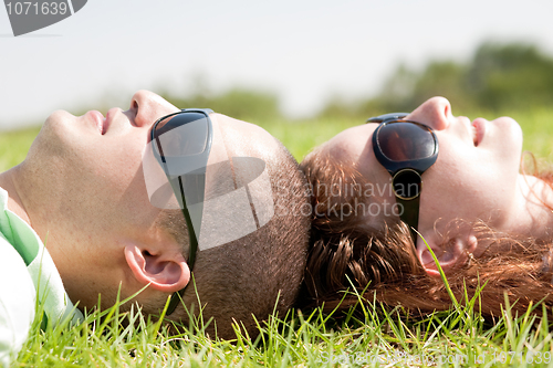 Image of Happy couple laying on a lawn and looks