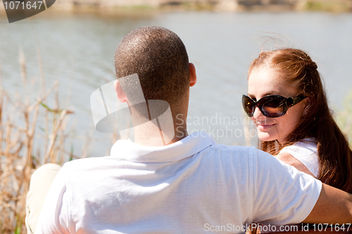 Image of Rear view of young couple sitting at the lake side