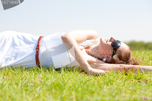 Image of happy young woman laying on a grass field