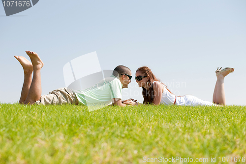 Image of Playful young couple laying on a grass lawn