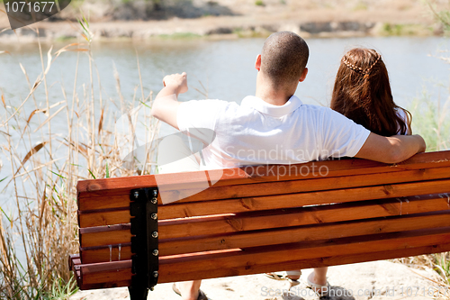 Image of young couple seated at the wooden bench