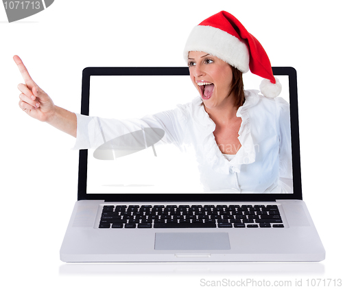 Image of Young happy santa girl pointing up through the laptop screen