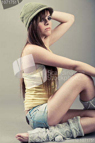 Image of Side pose of beautiful model sitting with green cap