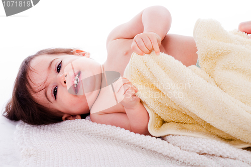 Image of Little smiling baby lying in white towel and wrapped with yellow towel