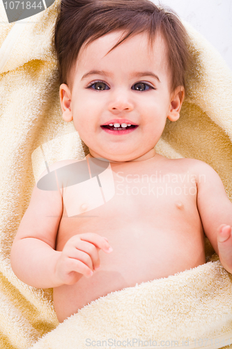 Image of Cute baby smiling covered in yellow towel