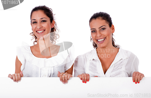 Image of Happy young business colleagues holding a white blank board