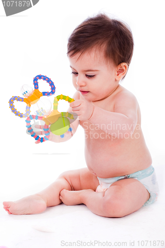 Image of Baby sitting with diaper and playing with toys