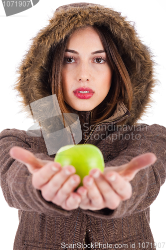 Image of Beautiful young lady showing green apple wearing a fur coat with head cap