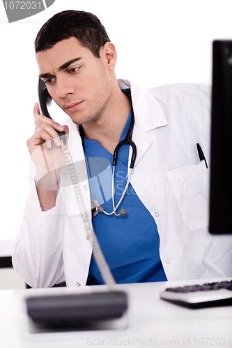 Image of Caucasian male doctor sitting at the desk with computer talking over phone