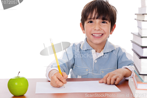 Image of School boy doing his homework with an apple beside him