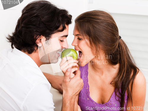 Image of closeup of young couple biting green apple