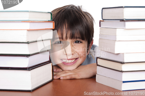 Image of Happy young school boy surrounded by books