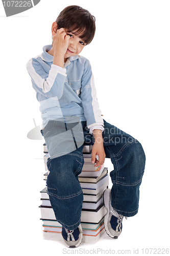 Image of Young boy sitting over tower of books