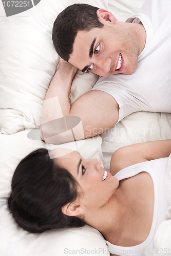 Image of Young smiling romantic couple lying in bed