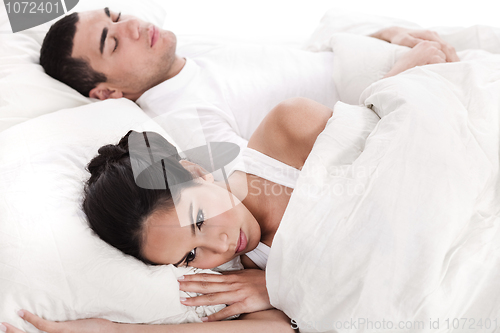 Image of Couple in bed, men sleeping and woman lying disappointed