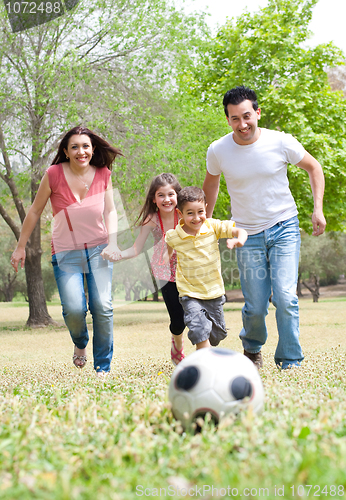 Image of Parents and two young children playing soccer in the green field