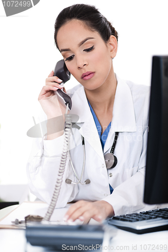 Image of Beautiful female doctor trying the phone very seriously