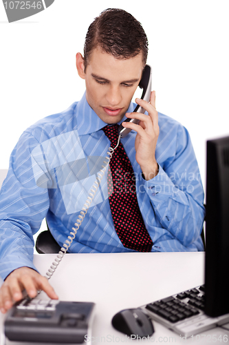 Image of young business man sitting at his desk talking over phone