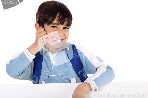Image of Smiling young boy acts as he talks over phone