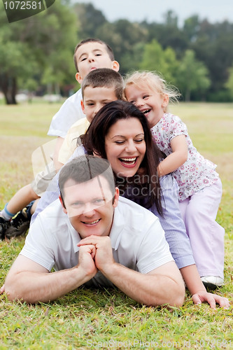 Image of Happy family piled up  on the park and looking at you