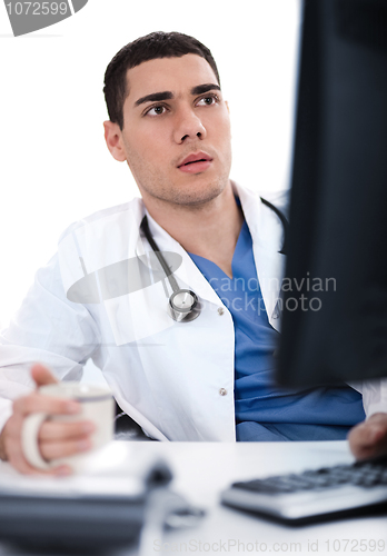 Image of Young ethnic doctor looking deeply at the computer