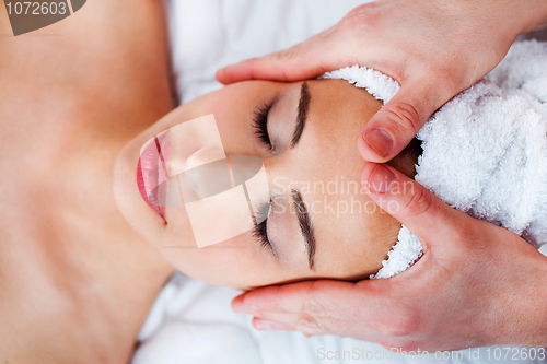 Image of Young pretty girl getting face massage in spa