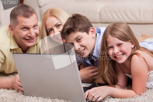 Image of Domestic family lying in living room with lap top