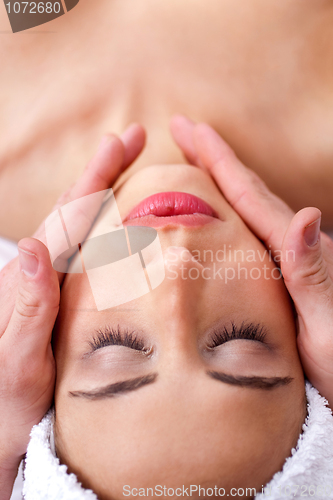 Image of Beautiful young  woman getting face massage and relaxing in spa
