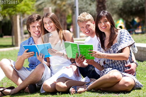 Image of Smiling young couple holding books posing to camera