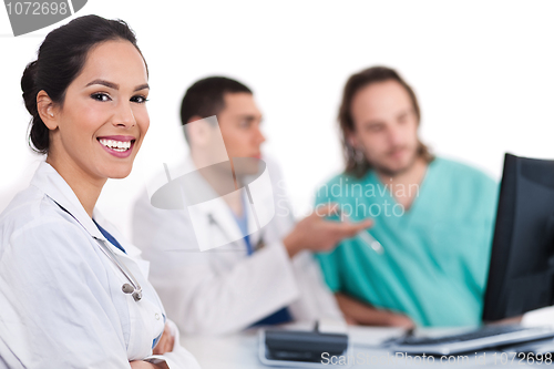 Image of Smiling young doctor with other doctors behind her