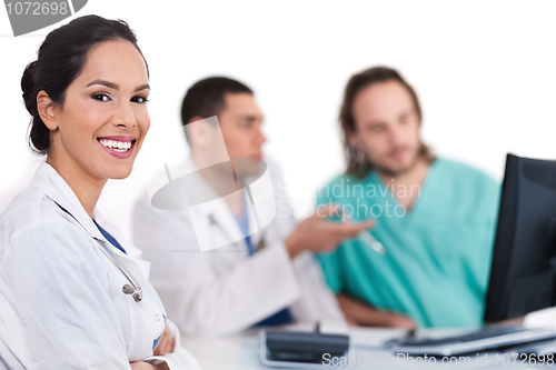 Image of Smiling young doctor with other doctors behind her