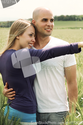 Image of Young couple in meadow with the hands in the air, hugging