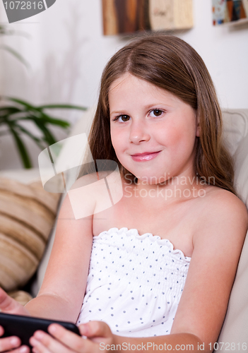 Image of Young smiling girl looking at you in living room