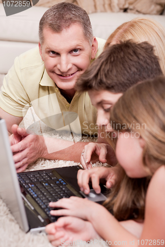 Image of Happy family lying and working with lap top