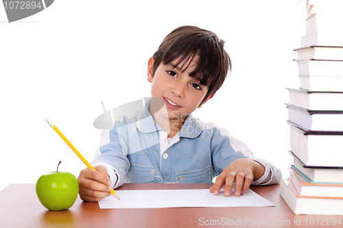 Image of School boy doing his homework with an apple beside him