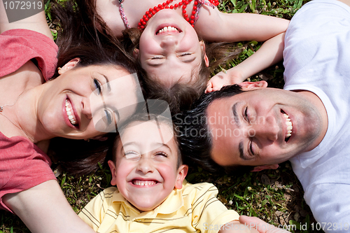 Image of Happy family laying in the circle on green grass