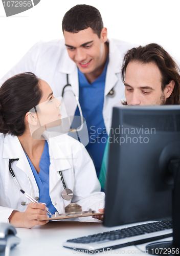 Image of Young doctors team discussing and making notes from computer