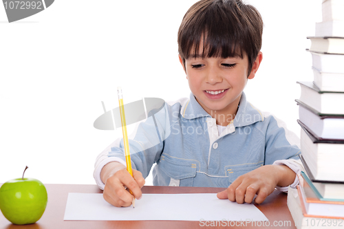 Image of School boy doing his homework with an apple beside him