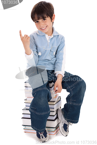 Image of Young boy sitting over tower of books