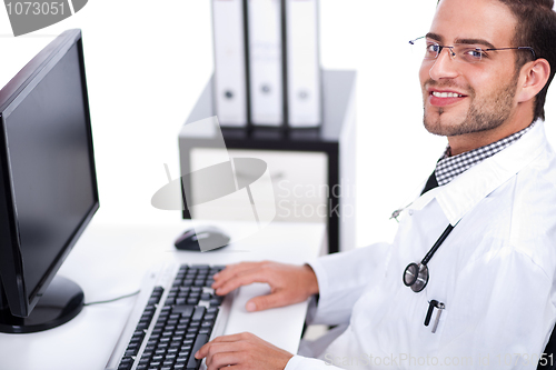 Image of Smiling young doctor working on his desk