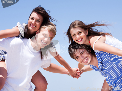 Image of Young men and women piggy back and having fun